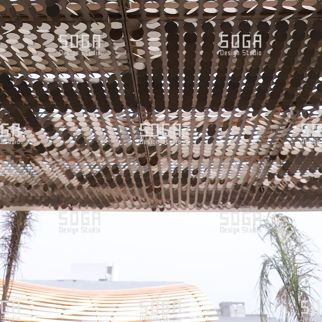 Backlit underside of a coin facade canopy showing the treated edge condition of each disc