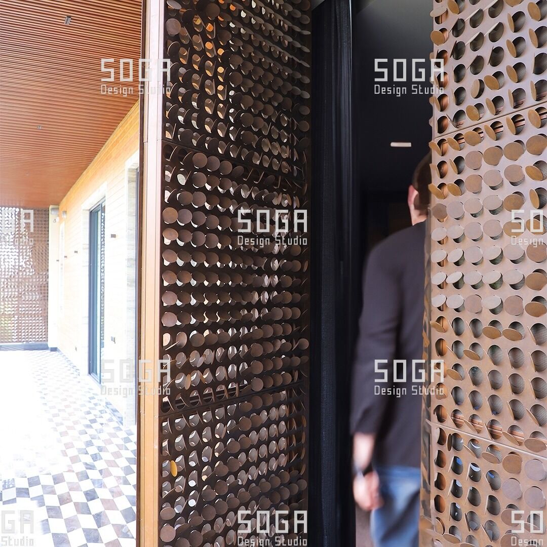 SOGA Coin Facade: The Complete Guide to Circular Parametric Metal Panels 8 Person walking past a coin facade screen at a building entrance, showing filtered view-through between discs