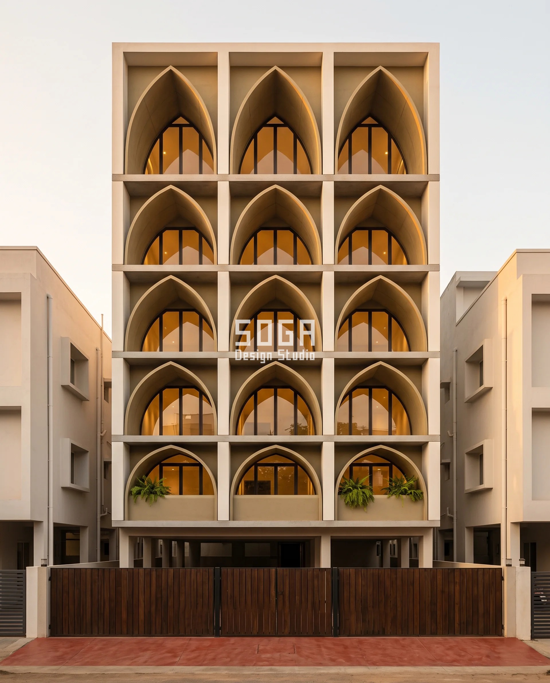 Khaki-tan GRC lancet vaults stacked six floors deep inside a recessed arcade on a narrow Erode plot, the pointed crowns rising floor by floor while the shadow slot behind the piers closes - facade projection in front setback India rules cap, won entirely behind the building line.