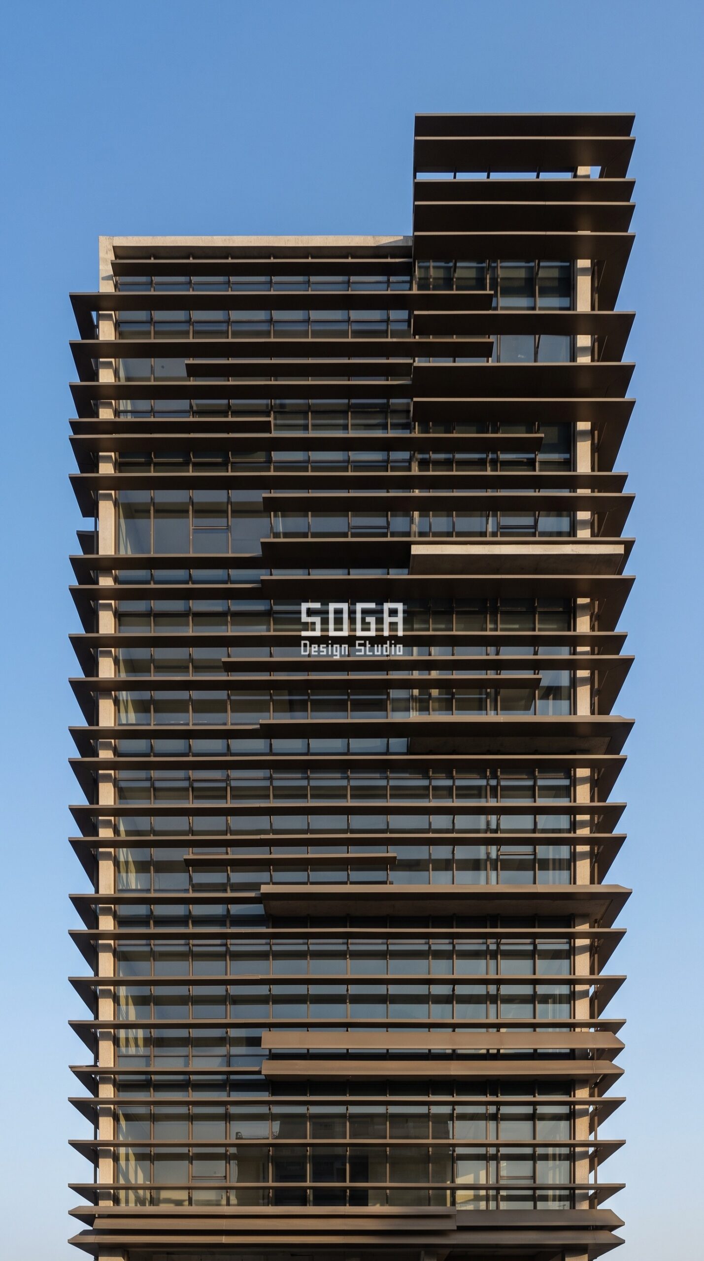 Why Facade Design Matters for Commercial Buildings 2026 2 Commercial office facade with deep bronze horizontal shading blades over glazing, Ahmedabad India - SOGA Design Studio
