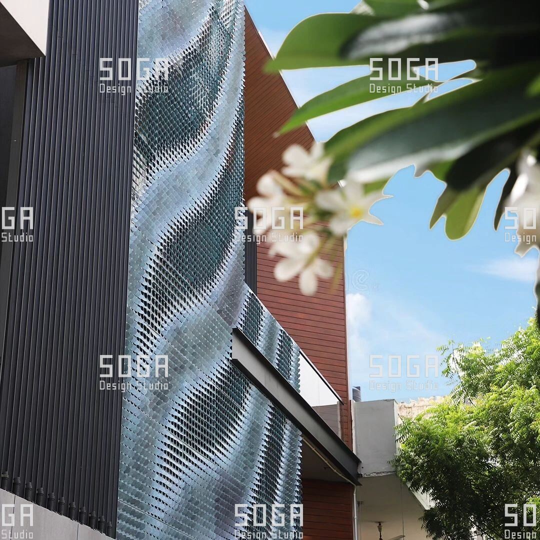 Coin Facade Design: The Parameters That Decide How a Coin Facade Looks 4 Metal disc screen seen through foliage, showing how spacing between coins sets how much light and view pass through